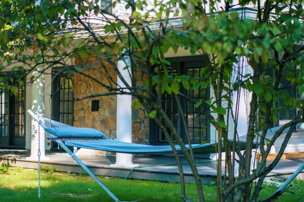 Un hamac dans un jardin, avec un bâtiment en pierre en arrière-plan.
