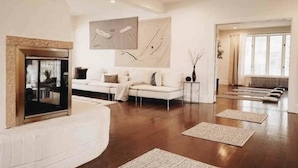 A spacious living room with a white sofa, a fireplace, and a large window. - The 212 Escape (Woodstock)