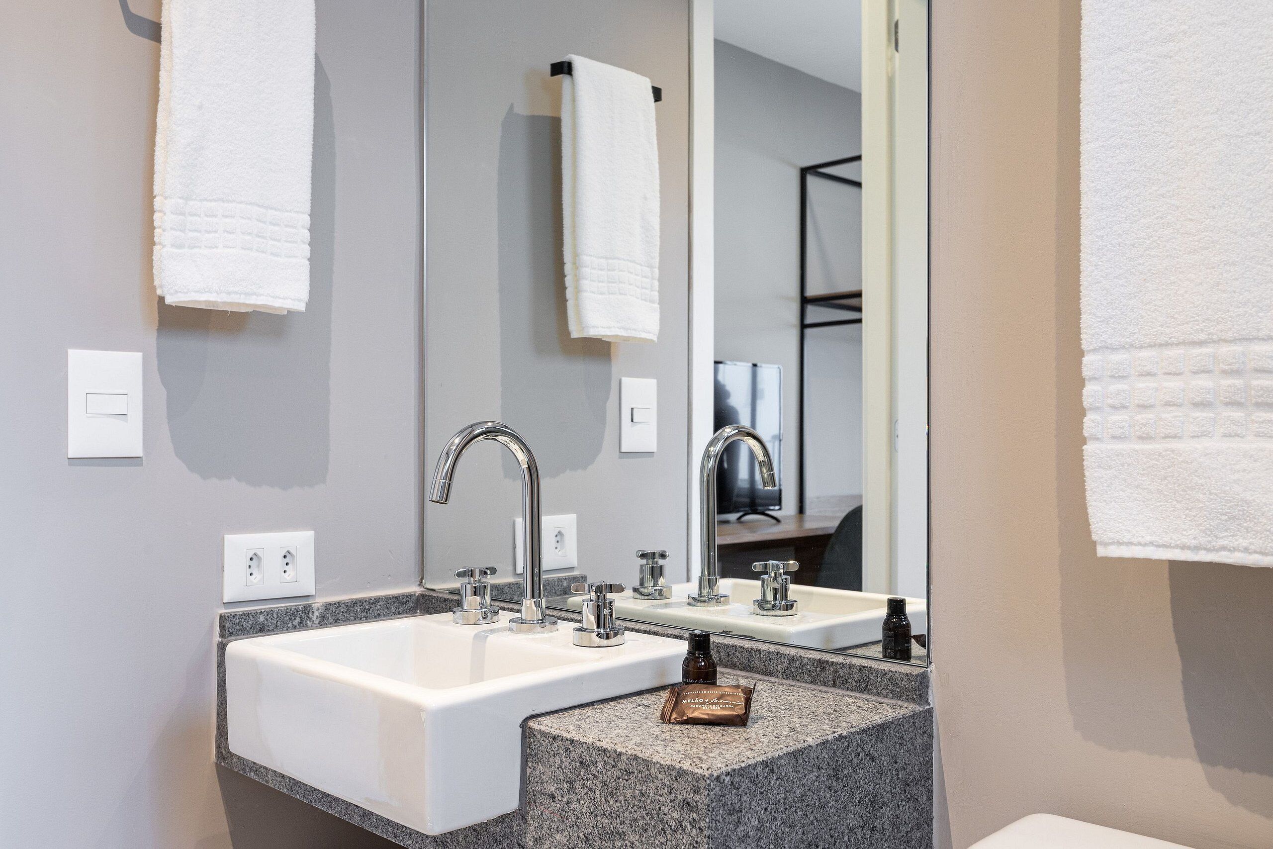 A bathroom with two sinks, a large mirror, and a towel rack.
