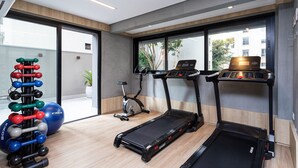 Een moderne sportschool met loopbanden, een crosstrainer en een set gewichten.