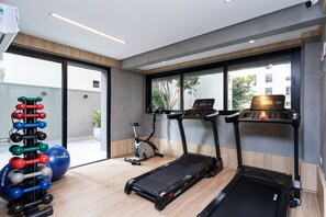 Un gimnasio moderno con cintas de correr, elípticas y un juego de mancuernas.