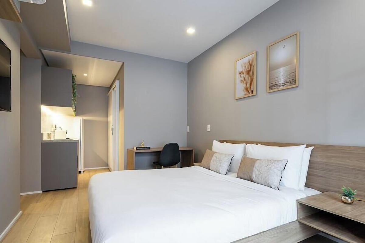 Ein modernes Hotelzimmer mit einem großen Bett, einem Schreibtisch und zwei gerahmten Bildern an der Wand.