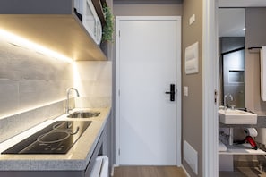 A modern kitchen with a built-in stove, a sink, and a white door.