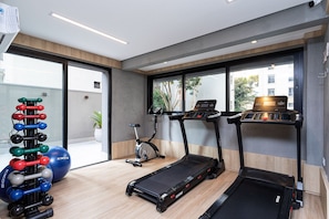 A modern gym with treadmills, an elliptical, and a set of dumbbells.