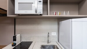 Een moderne keuken met een ingebouwde magnetron, een roestvrijstalen spoelbak en een aanrecht met een koffieapparaat.