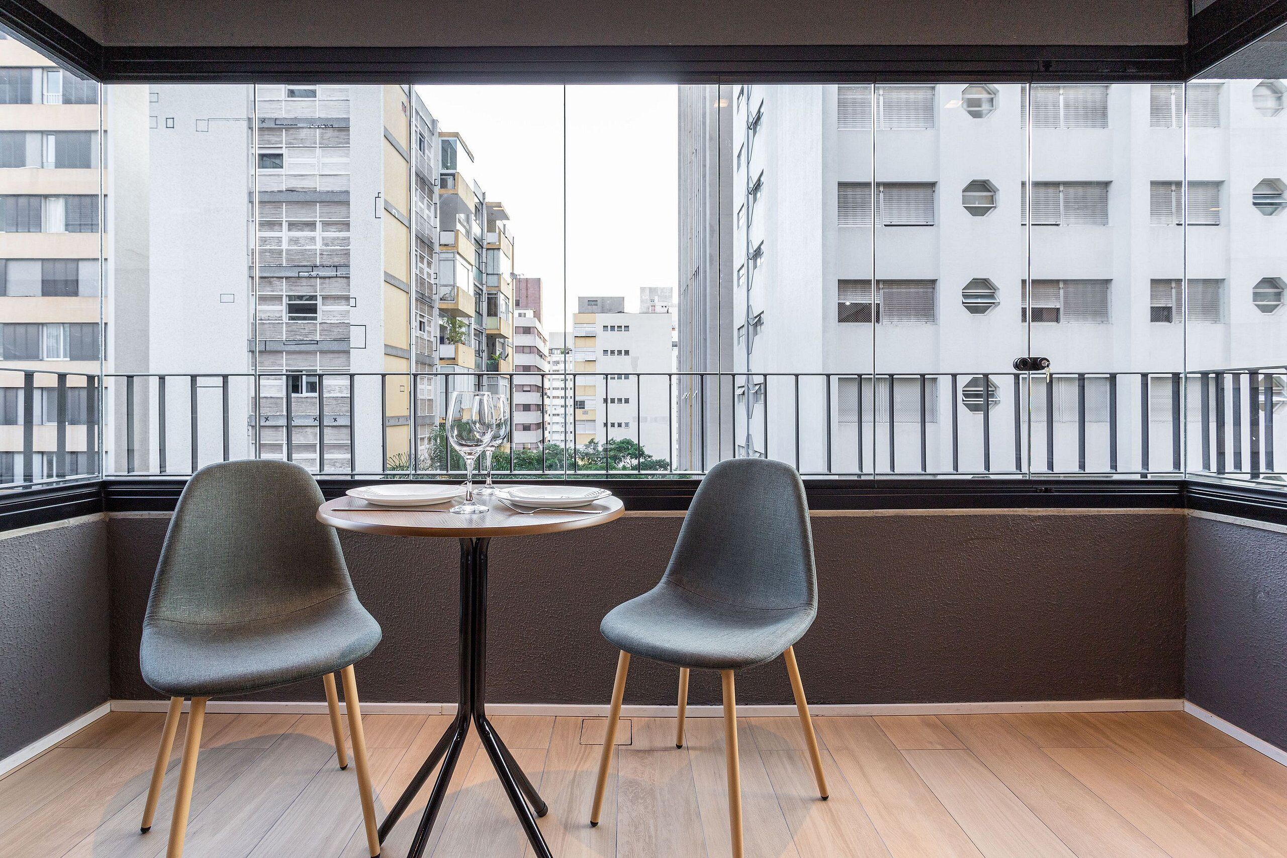 Un balcone con due sedie, un tavolo e vista su edifici alti.