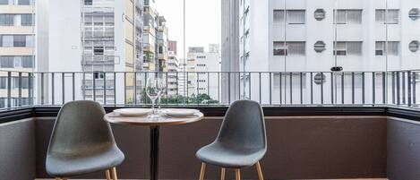 Un balcone con due sedie, un tavolo e vista su edifici alti.