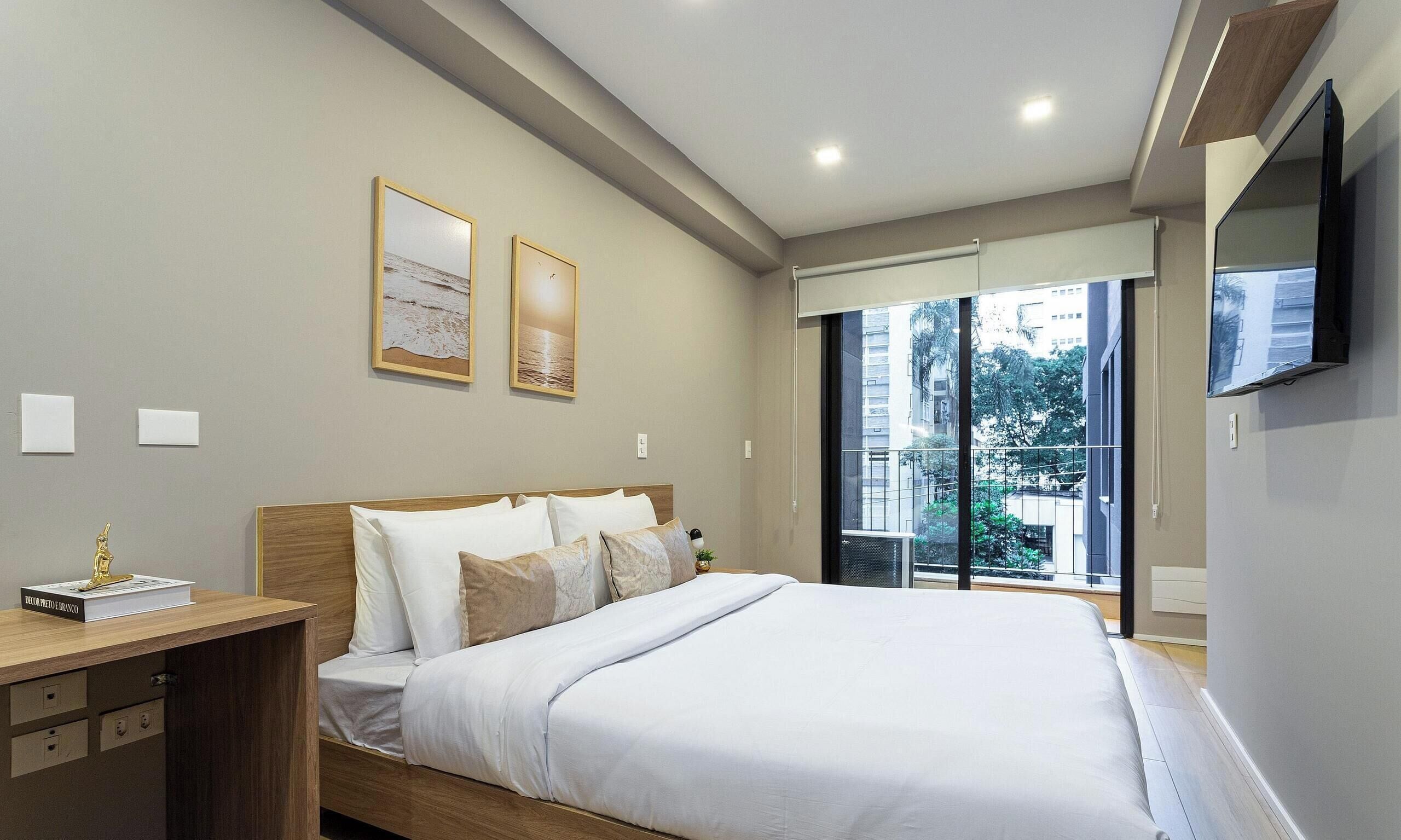 A modern bedroom with a bed, bedside table, and a TV mounted on the wall.