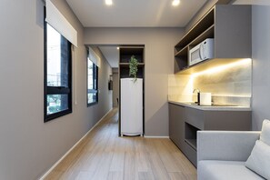 Cozinha moderna com eletrodomésticos embutidos, área de estar e corredor que dá para outro quarto.