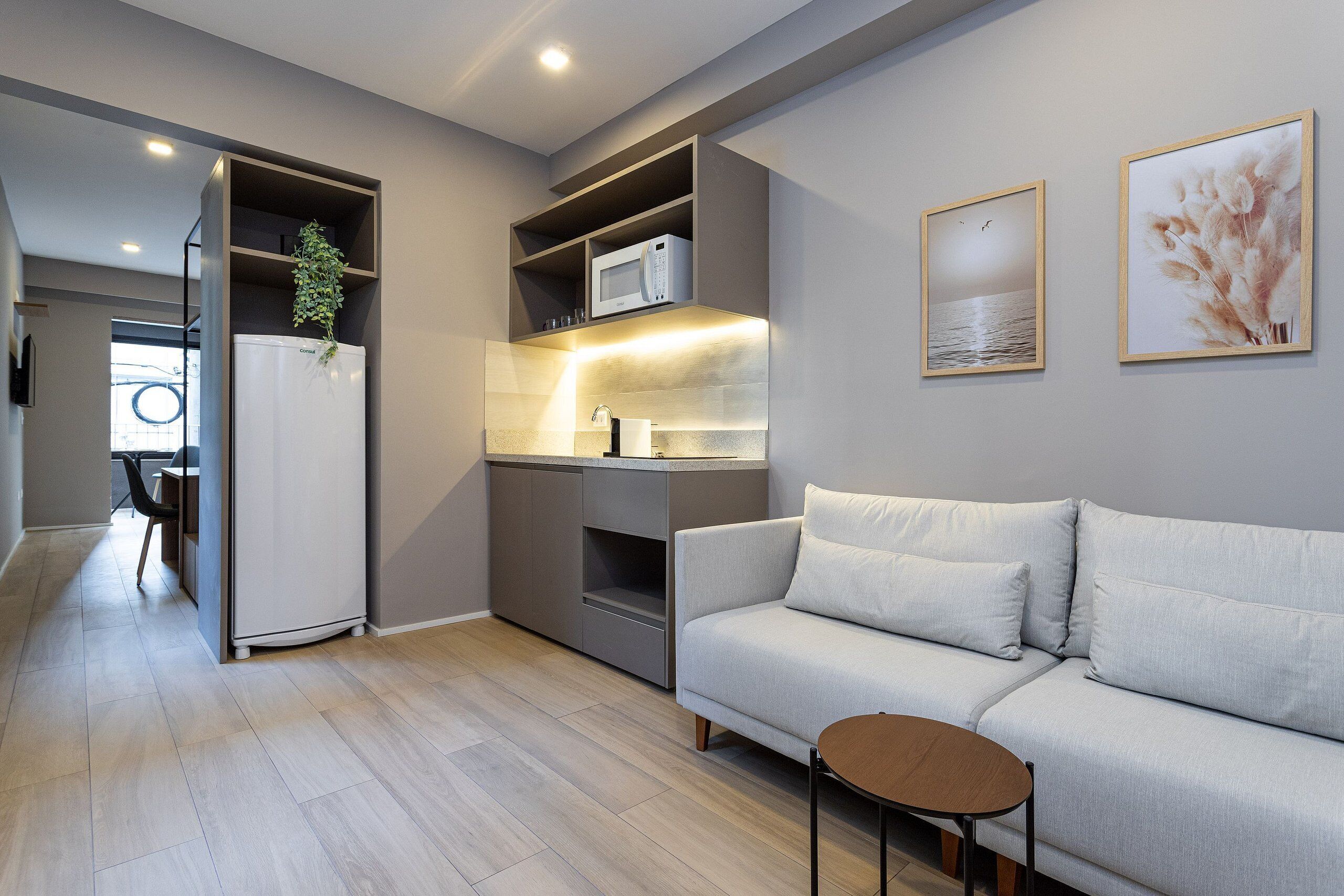 Une cuisine moderne dotée d’appareils électroménagers intégrés, un canapé gris et un coin repas avec une chaise.