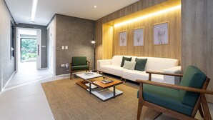 Een moderne woonkamer met een witte bank, een groene fauteuil en een salontafel.