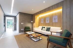 Una sala de estar moderna con un sofá blanco, un sillón verde y una mesa de centro.