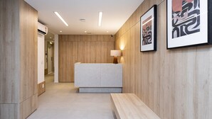 A modern reception area with a wooden reception desk, a bench, and framed artwork on the wall.