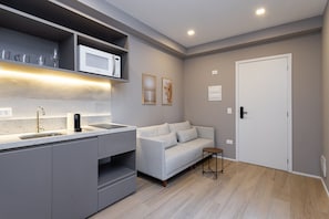 Una cocina moderna con microondas integrado, un lavabo y una pequeña mesa.