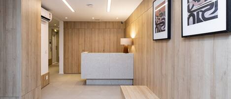 A reception area with a wooden reception desk, a bench, and framed artwork on the wall.