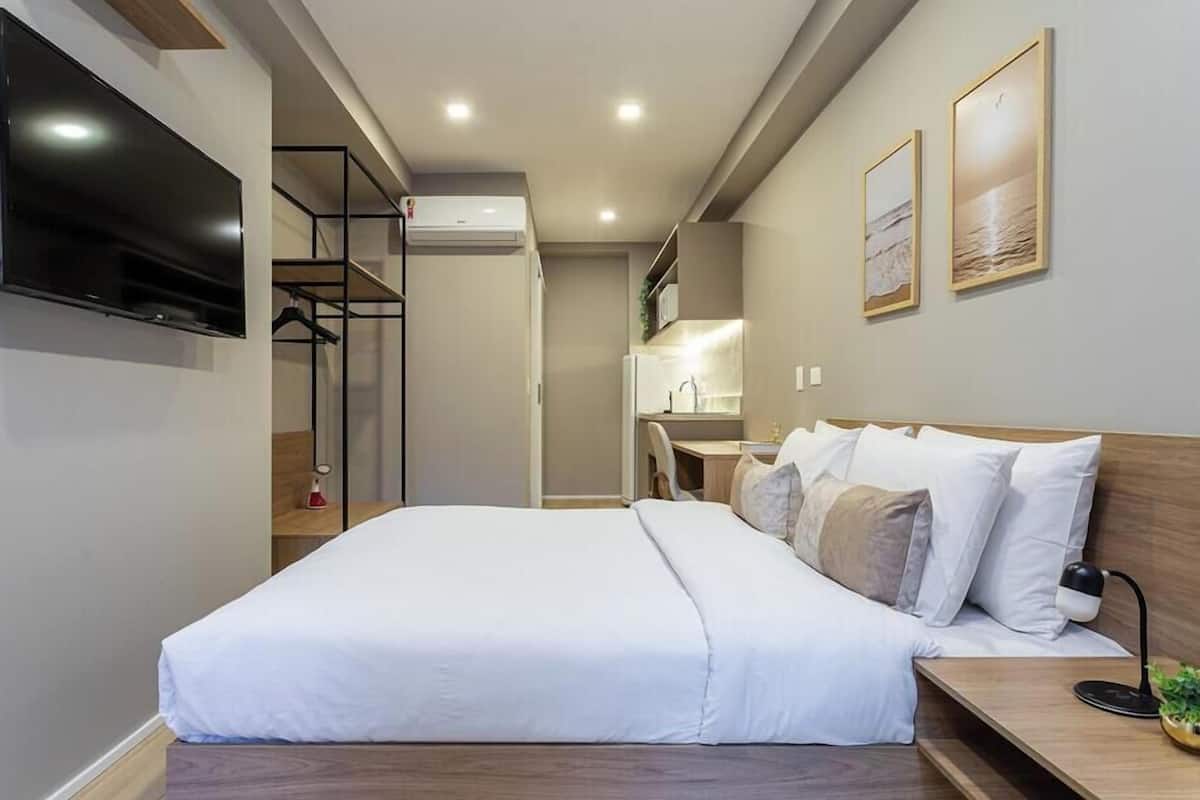 Une chambre d’hôtel avec un lit, un bureau, une télévision et une petite plante.