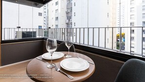 A dining table with plates and cutlery, a chair, and a window with a view of a building.