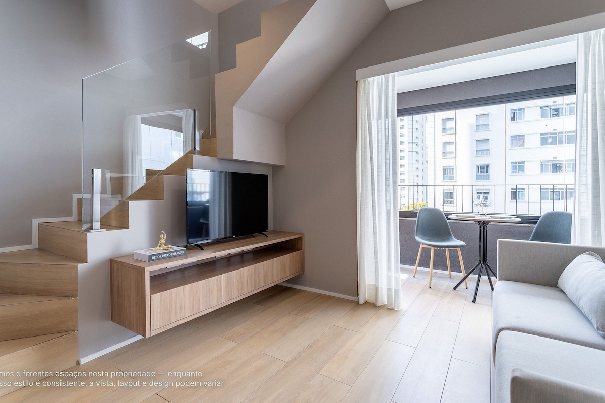 Ein modernes Wohnzimmer mit Fernseher, einer Holz-Unterhaltungsanlage und einem Balkon mit Tisch und Stühlen.
