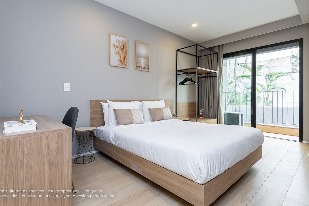 Une chambre moderne avec un grand lit, un bureau et un balcon offrant une vue agréable.