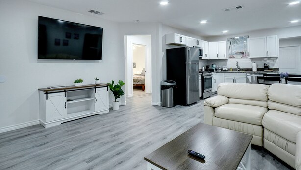 A modern living room with a flat-screen TV, a sofa, and a coffee table. - Step Into Paradise (River Oaks)