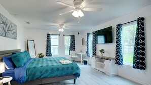 A bedroom with a bed, ceiling fans, a desk, and a TV. - Step Into Paradise (River Oaks)