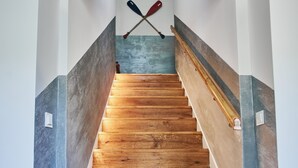 Un escalier en bois, doté d’une rampe et d’une paire de pagaies accrochées au mur au-dessus.