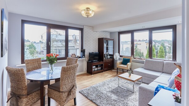 Un salon spacieux comprenant un coin repas, de grandes fenêtres, un téléviseur et un canapé.
