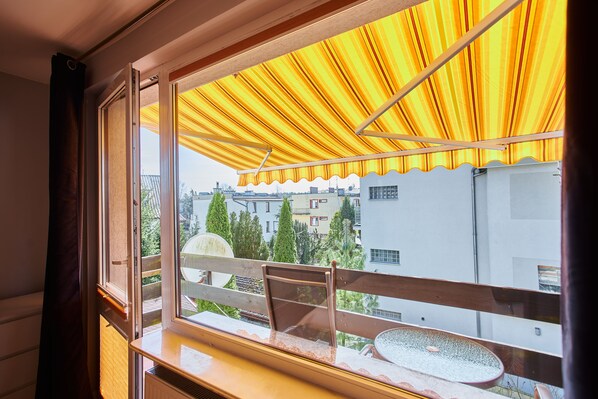A balcony with a yellow striped awning, a chair, and a table. - Apartamenty Swinoujscie - Chodorowskiej (Swinoujscie)