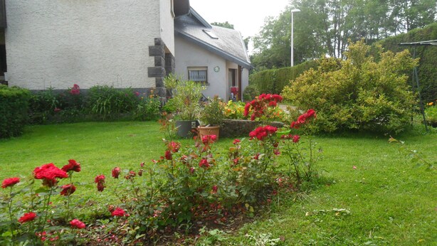 Ein Haus mit einem Garten, der rote Rosen und verschiedene Pflanzen zeigt.