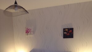 Ein Schlafzimmer mit einem Bett, zwei Nachttischen mit Lampen, einer Pendelleuchte, einer Blumenwanddekoration und einem gerahmten Bild.