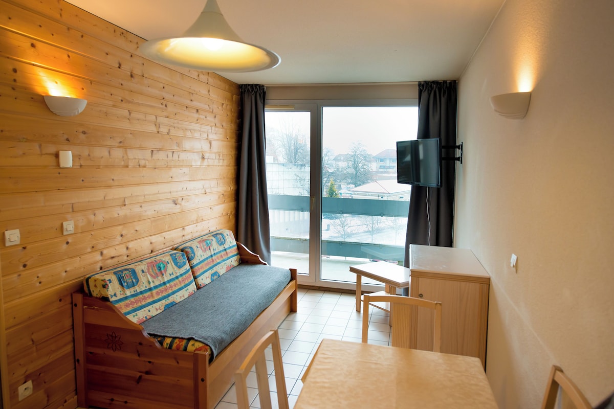 A cozy room with a wooden wall, a sofa, a small table, and a TV.