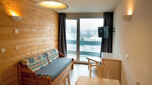 Una habitación acogedora con una pared de madera, un sofá, una mesita y un televisor.