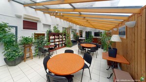 Un espacio interior amplio con techo de cristal, vigas de madera y diversas opciones de asientos.