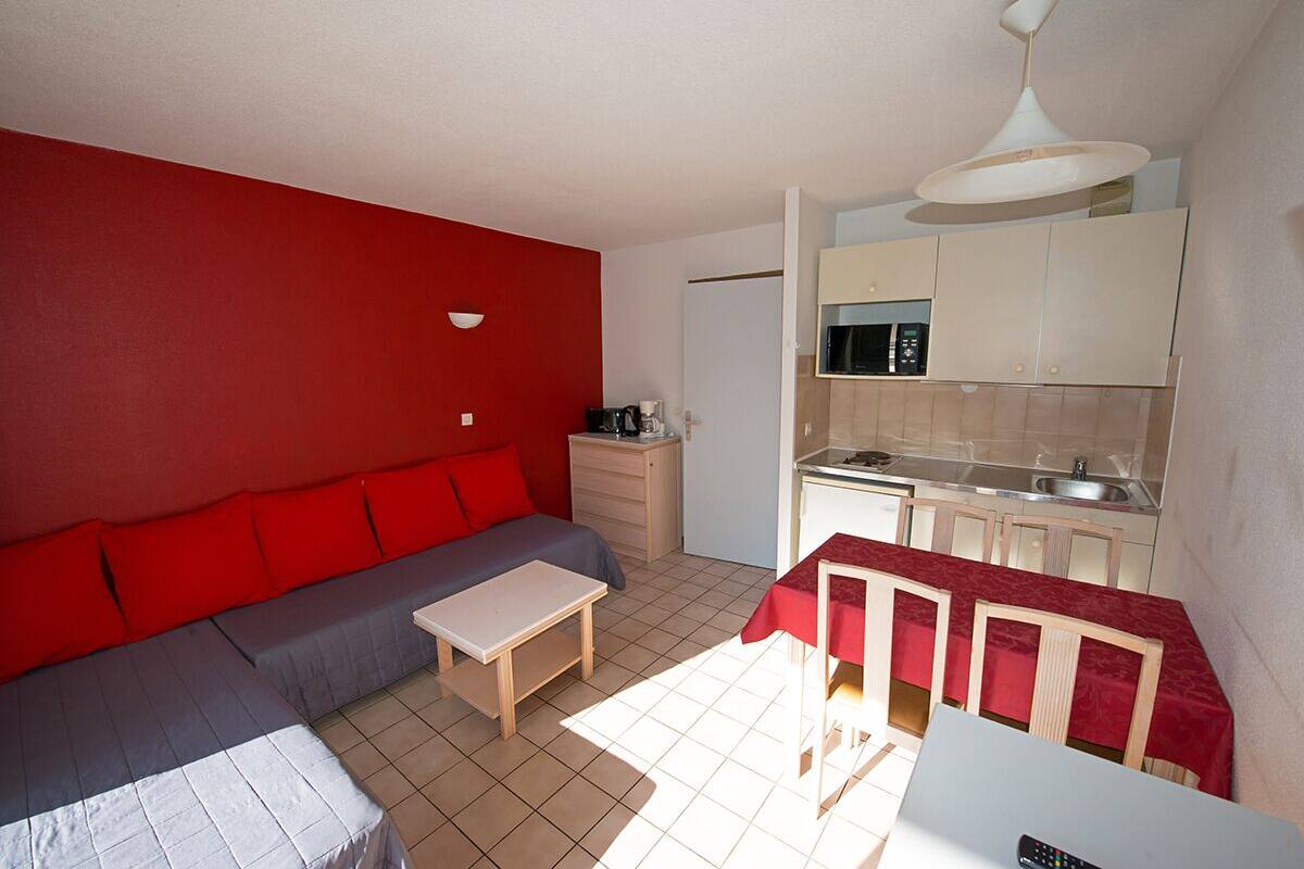 A compact living space with a kitchenette, a sofa, a dining table, and a small kitchen area.