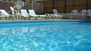 Una piscina con agua azul cristalina y sillones blancos bordeando la orilla.