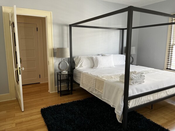A four-poster bed with white linens, a black rug, and two bedside lamps. - 3 bedroom Craftsman bungalow in the heart of Lakeland (Lakeland)
