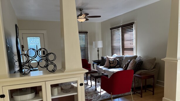 A living room with a sofa, red armchair, and a cabinet with shelves. - 3 bedroom Craftsman bungalow in the heart of Lakeland (Lakeland)