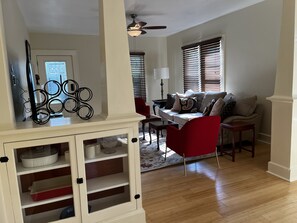 A living room with a sofa, red armchair, and a cabinet with shelves.