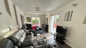 Ein Wohnzimmer mit Ecksofa, Couchtisch, Fernseher und Kamin.