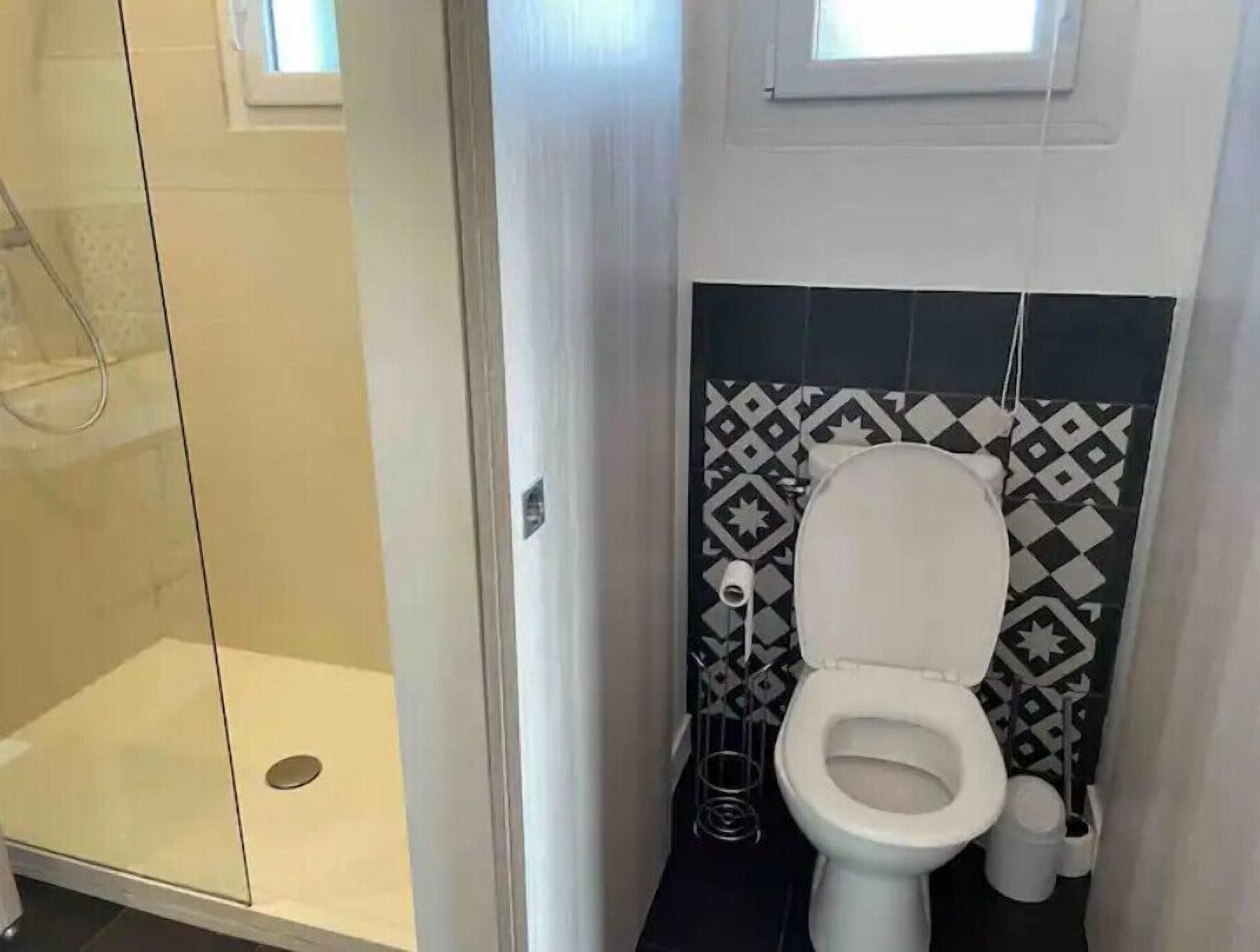 Un bany amb vàter, dutxa i un paper de paret amb dibuixos.