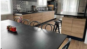 Eine moderne Küche mit schwarzem Arbeitsplatz, Holzschränken und einem Essbereich mit einem schwarzen Tisch und Stühlen.