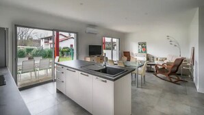 Una cucina moderna con una grande isola, porte scorrevoli in vetro che danno su un patio e un'area pranzo con una poltrona a dondolo.