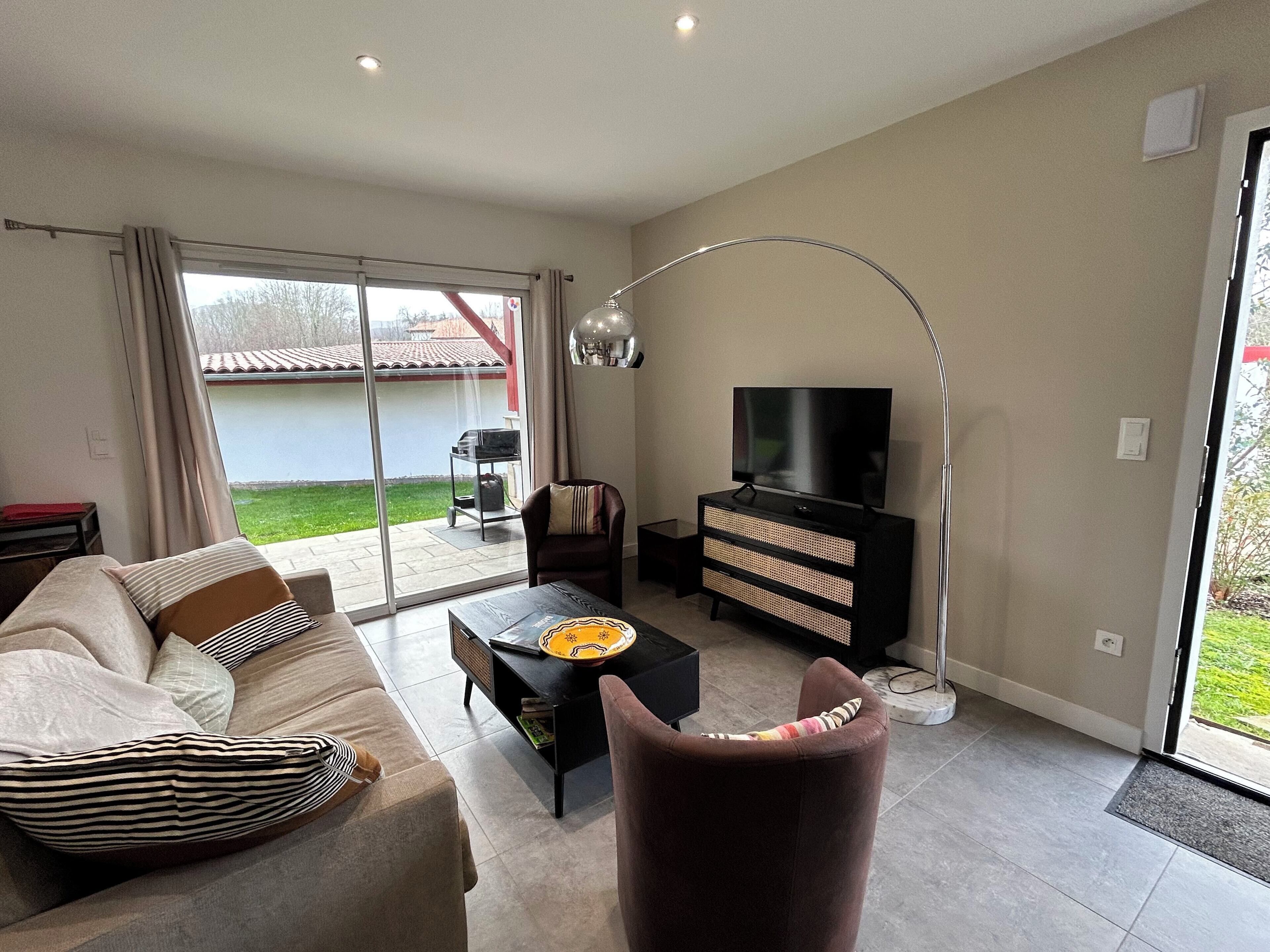 A modern living room with a sofa, coffee table, TV stand, and a large window.