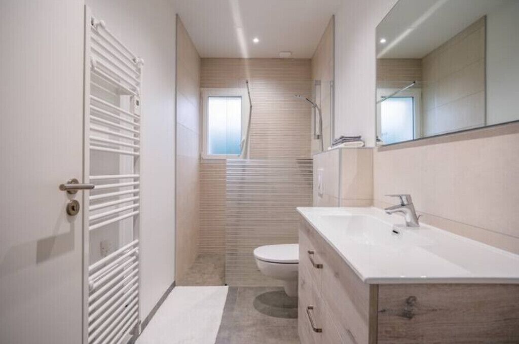 Une salle de bain moderne avec un meuble-lavabo blanc, des toilettes et un espace douche.
