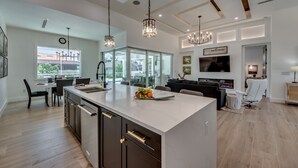 A modern kitchen with a large island, pendant lighting, and a dining area with a view.