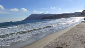 Uma praia com calçadão de concreto e mesas para piquenique.