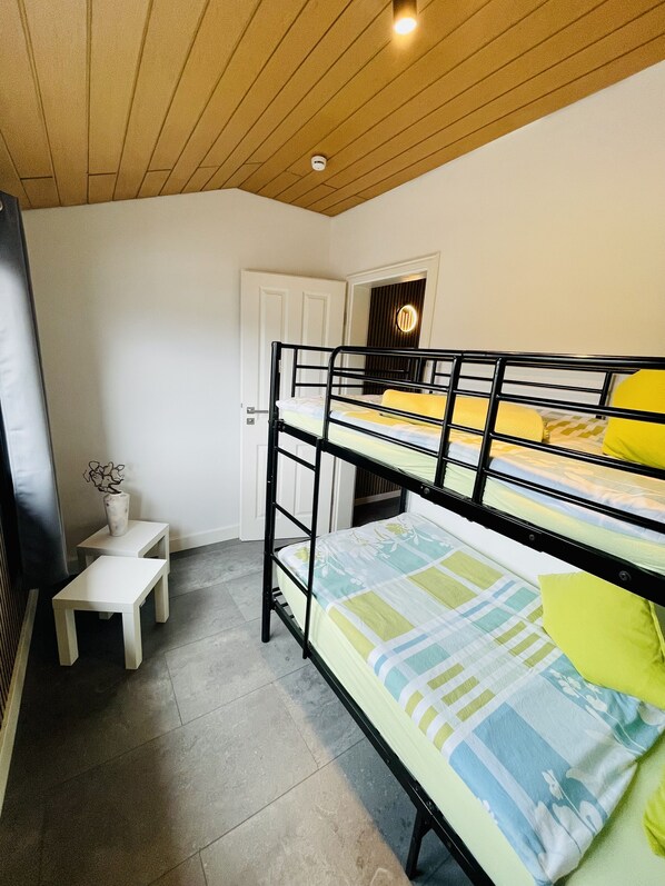Habitación con literas, una pequeña mesa blanca y un florero.