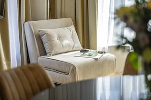 Una habitación bien iluminada con una cama, una revista sobre la cama y una ventana con cortinas.