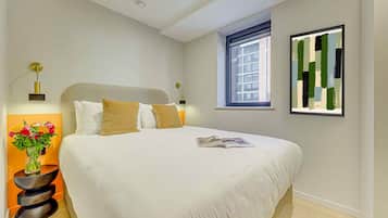 Une chambre moderne avec un grand lit, des lampes de chevet, une fenêtre et un tableau abstrait encadré.