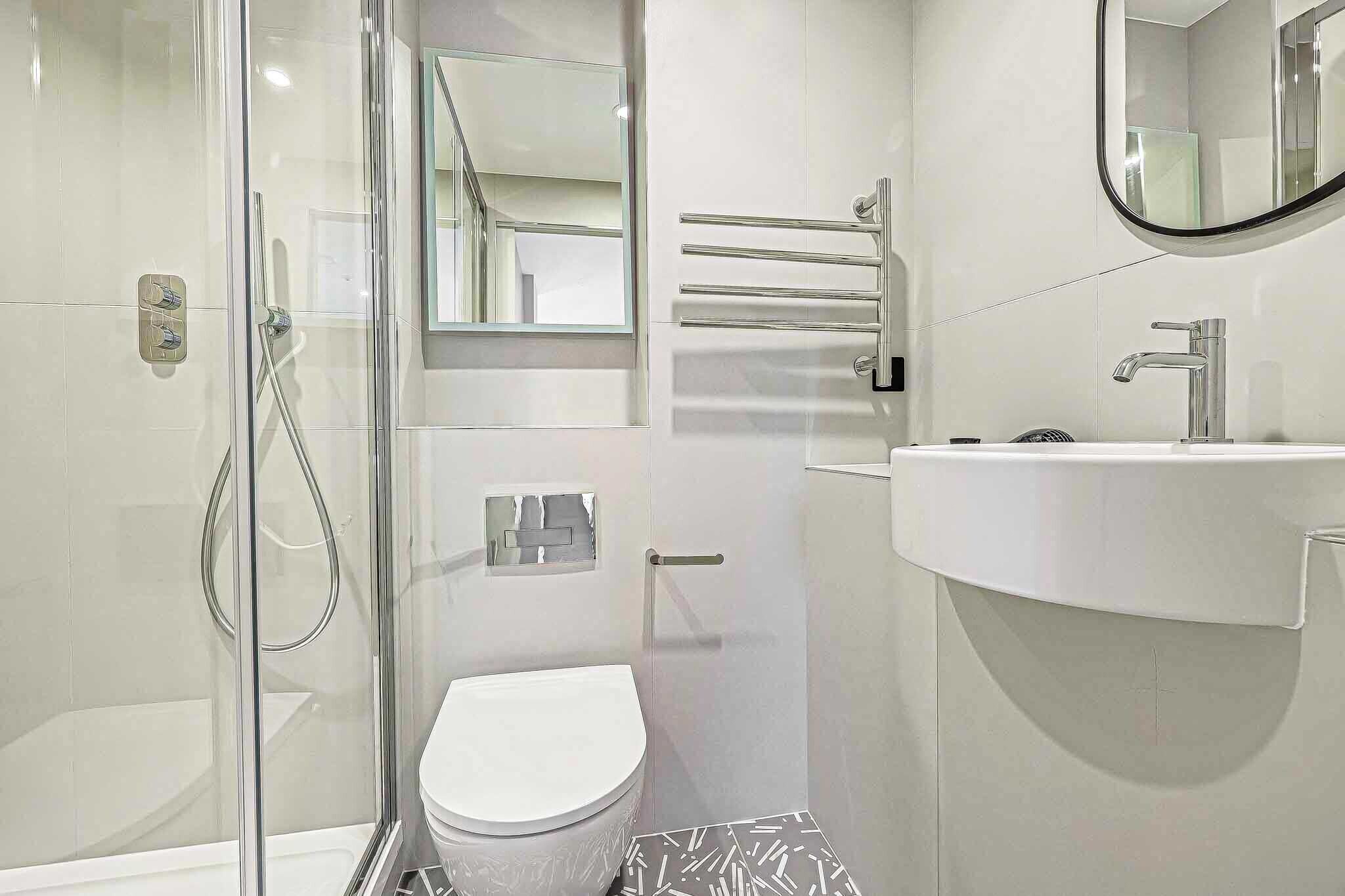 Un bany modern amb una cabina de dutxa de vidre, un vàter, un lavabo amb mirall i paraules d'agulla.